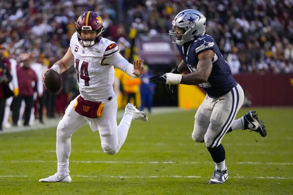 Washington Commanders quarterback Sam Howell (14) running away from Dallas Cowboys linebacker Micah Parsons (11) during the first half of an NFL football game, Sunday, Jan. 7, 2024, in Landover, Md. (AP Photo/Mark Schiefelbein)
